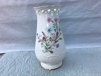 Front view of the large white porcelain Aynsley vase with floral pattern and ribbed base.