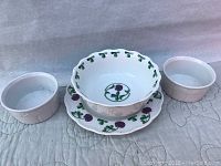 View of four vintage Dansk porcelain pieces, including a scalloped bowl, plate, and two ramekins, all featuring purple floral design.