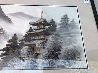Close-up showing pagoda and detailed hand-stitched embroidery on the silk tapestry with a misty mountain background.