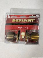 Front of packaged Defiant keyed entry brass door knob set