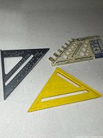 Group shot of three speed squares: grey metal, yellow plastic, off-white plastic
