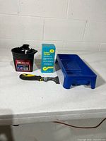 Full lot view: paste box, blue paint tray, black trim cup, scraper