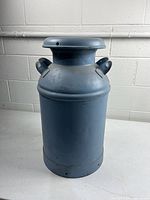 Front view of blue metal milk can with lid and handles