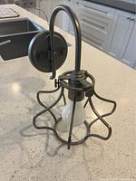 Side view of metal sconce showing curved arm, backplate, and cage shade with bulb