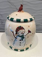 Jar front showing snowman graphic, striped rim, cardinal lid