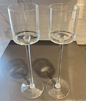 Pair of tall clear glass candleholders on countertop