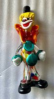 front view of multicoloured glass clown figurine showing top hat, face, collar, buttons and feet