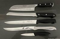 Top-view of five stainless steel kitchen knives showing blade types and handles