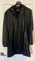 Front view of black leather coat hanging, showing buttons and collar