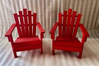 Two red wooden miniature Adirondack chairs side by side on neutral background