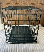 Front view of black wire dog crate showing plastic base pan inserted