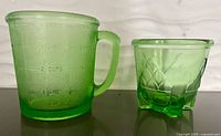Both green glass measuring cups, side by side