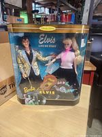 Front of boxed Barbie Loves Elvis collector edition set showing both dolls and graphics