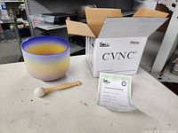 Singing bowl, mallet, certificate and box on table