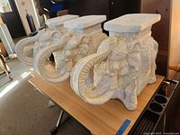 Three white ceramic elephant plant stands on a table