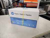 Angled view of sealed HP Office20 paper box showing branding, strap and product icons