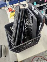 Milk crate containing stacked Logitech keyboards and visible mice cable