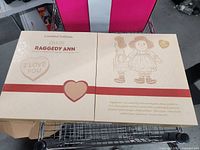 Front of beige presentation box showing Dakin Raggedy Ann Limited Edition graphics and heart motifs