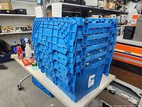 Stack of five blue lock-lid totes on a table