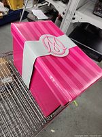 Closed pink striped box with white MO monogram sleeve