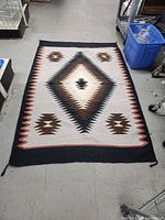 Full view of woven rug showing overall pattern and size relative to floor tiles