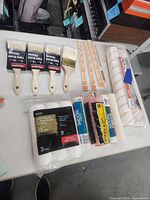 Overview of brushes, roller covers, stir sticks, masking tape laid on table