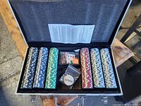 Open case showing all contents: sealed chip rolls, card deck, dealer button