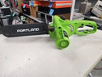 Full view of green Portland electric chainsaw showing bar cover and body