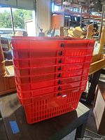 Stack of eight red plastic shopping baskets