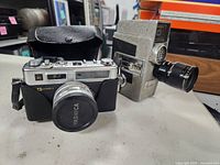Yashica rangefinder camera with leather case beside grey 8mm movie camera
