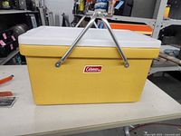 Front view of yellow Coleman cooler showing logo and handles
