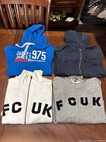 All four hoodies laid out on table showing colors and front designs