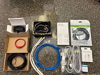 All items laid out including boxed and packaged cables, loose Ethernet cables, charging cords, wall charger, earphones