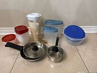Lot overview showing cookware and plastic storage pieces