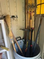 Long-handle tools in barrel: weed puller, hoe, broom, cultivator