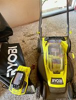 Top view of Ryobi mower, battery bay, charger, grass bag