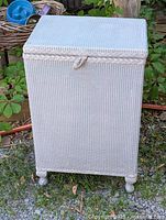Front view of painted wicker hamper showing overall form and feet