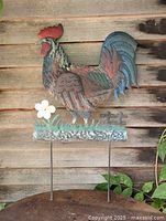 Full view of painted metal rooster stake against wood wall