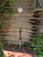 Full view of lightning rod on iron tripod base beside wooden wall
