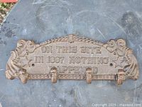 Front view of cast iron key rack showing inscription and hooks