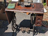 Full view of sewing machine on cabinet with manual on surface