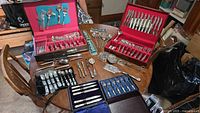 Overview of all boxed flatware, serving utensils and loose pieces on table