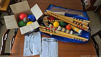 Overview of bocce balls in box, croquet components in blue case, manuals visible