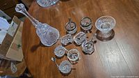 Group view of all crystal pieces including decanter, nine condiment dishes with spoons, and bell