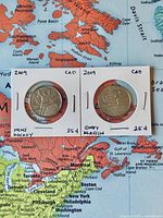 Front view of both Olympic 25 ¢ coins showing reverse designs and dates