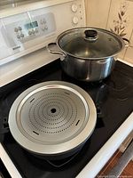 Stock pot with glass lid and perforated insert on stovetop