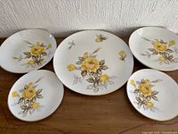 Five Cotillion yellow rose plates and bowls displayed front