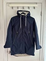 Front view of navy LOAP jacket hanging, hood up, pockets visible
