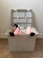 Open bin showing fabric scraps, pink yarn, pin holders and braided trim