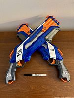 Two NERF Rough Cut 2x4 blasters crossed, darts loaded